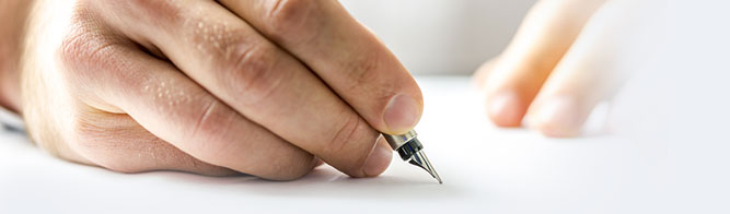 Close-up of a hand writing on white paper with a fountain pen